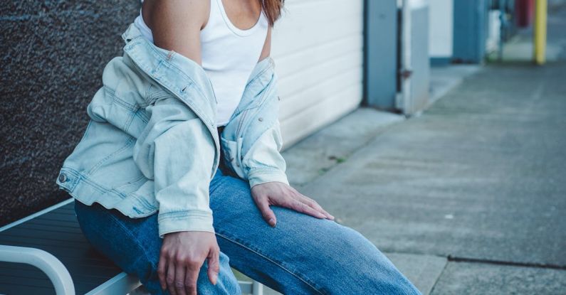 Styles - A woman sitting on a bench in front of a building