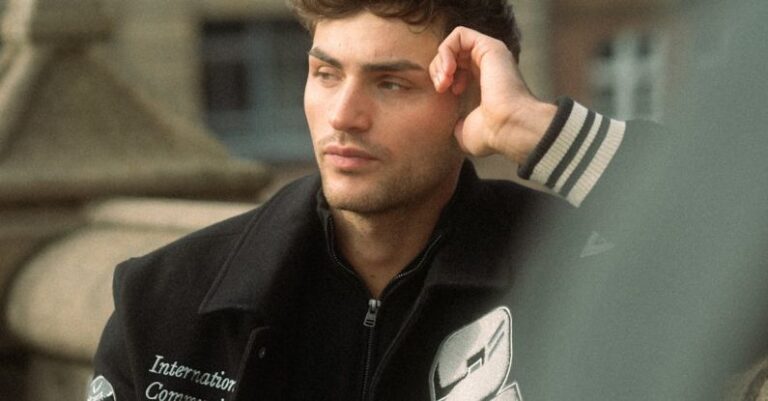 Styles - Young Man in a Baseball Jacket Standing on the Background of Building in City